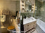 Before and after photo of a small London bathroom renovation by Design Angels, showing transformation from dated tiles to a modern green and brass design